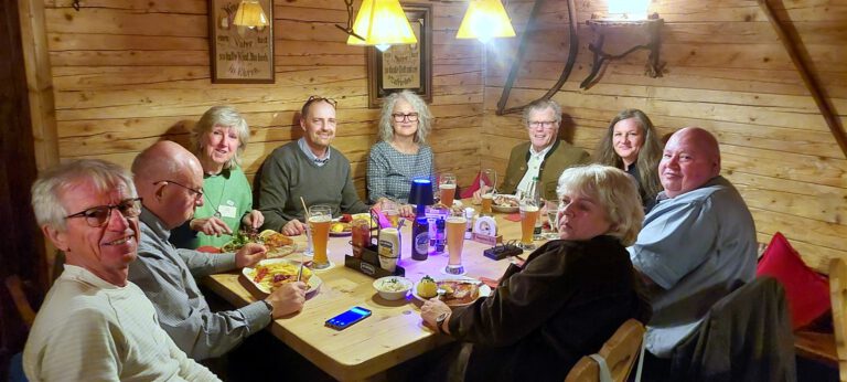 Gemeinsames Abendessen im Gasthaus: Teilnehmende des Symposiums sitzen an einem langen Holztisch zusammen